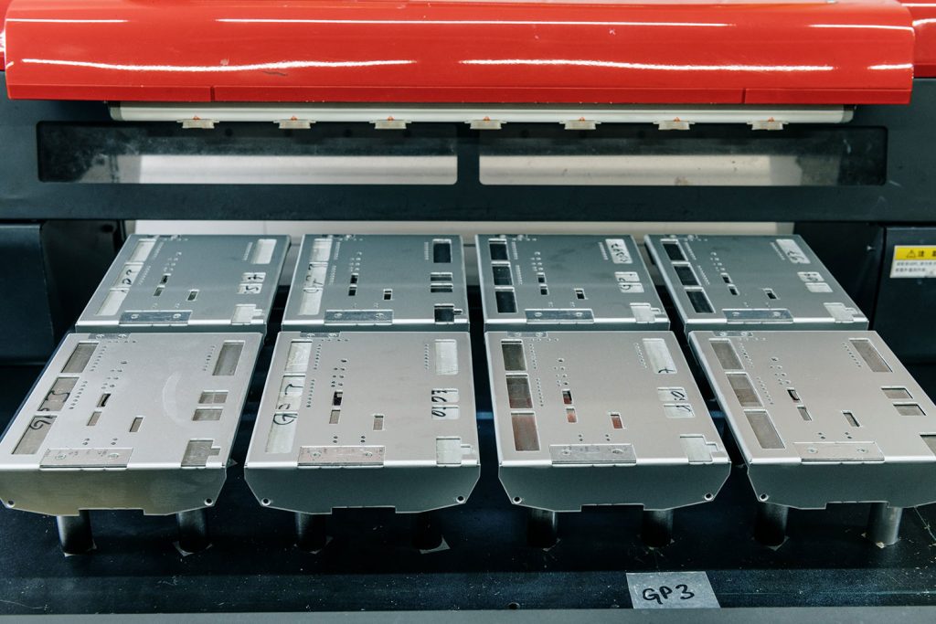 Roter Digitaldrucker mit einer Vorrichtung, die mit acht Metallteilen bestückt ist.