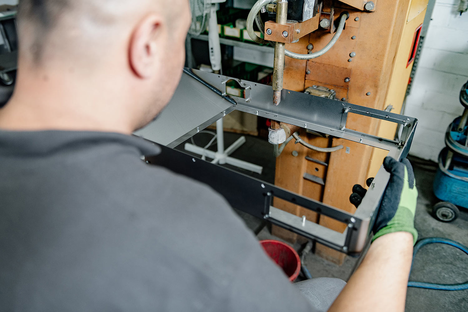 Mitarbeiter verbindet Teile eines Metallgehäuses an einer Punktschweißmaschine.