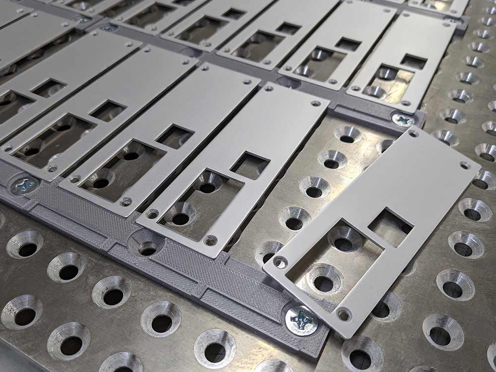 Frontplatten die reihenweise auf Vorrichtungen aus dem 3D-Drucker liegen.