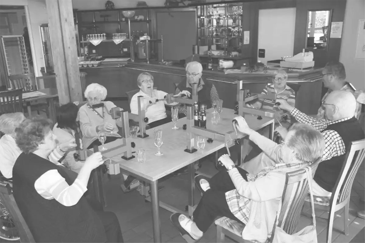 Schwarz-Weiß Foto von Senioren, die in einer Senioreneinrichtung am Plaudertisch sitzen