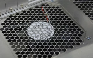 Metall-Schutzgitter mit Wabenstruktur vor einem eingebauten Elektroniklüfter